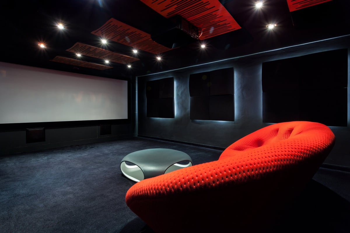 Cine en casa acogedor con sofá rojo en ambiente oscuro e íntimo